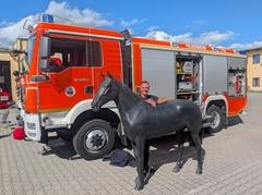 Feuerwehrmann mit Pferdedummy vor einem Feuerwehrfahrzeug