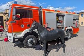 Feuerwehrmann mit Pferdedummy vor einem Feuerwehrfahrzeug