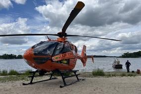 Hubschrauber im Vordergrund. Hinten Wasser und Feuerwehrboot