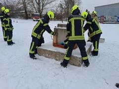 Arbeiten am Steinblock, mehrere Feuerwehrmänner packen an