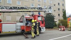 2 Feuerwehrmänner vor der Drehleiter. Sie setzen gerade die PA Flaschen auf.