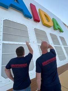 Feuerwehrmänner vor dem Logo der AIDA