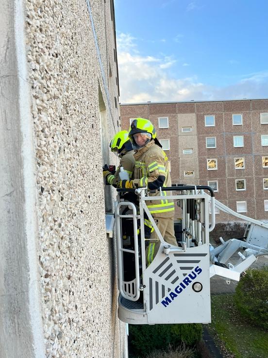 Zwei Feuerwehrleute im Korb einer Drehleiter. Sie befinden sich an einem Fenster.