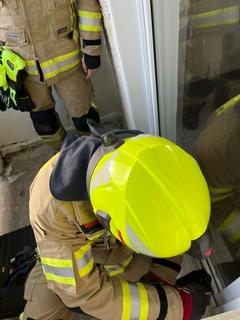 Eine Galstür am Balkon ist verschlossen. Feuerwehrmann versucht sie aufzubrechen