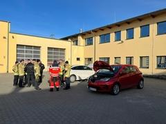 Feuerwehrmänner im Innenhof der Wache vor Hybridfahrzeugen