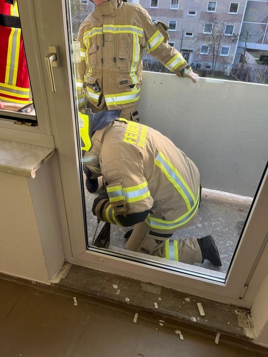 Eine Galstür am Balkon ist verschlossen. Feuerwehrmann versucht sie aufzubrechen