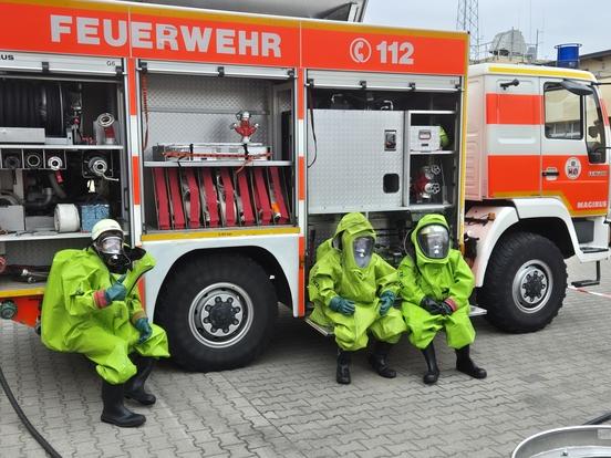 Drei Feuerwehrmänner im Schutzanzug am Auto