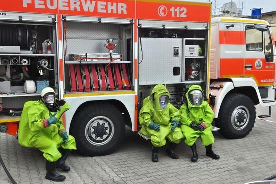 Drei Feuerwehrmänner im Schutzanzug am Auto