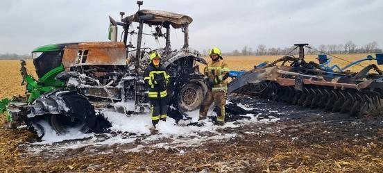 Zwei Feuerwehrmänner vor einem abgelöschten Traktor