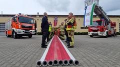 Feuerwehrmänner stehen Spalier. Links und rechts steht ein Feuerwehrfahrzeug. Es ist bewölkt