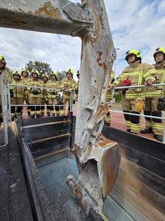 Bagger und Feuerwehrmänner an Übungsanlage
