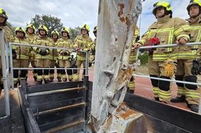 Bagger und Feuerwehrmänner an Übungsanlage