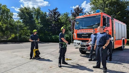 Feuerwehrmänner mit Sicherungsleine vor einem Feuerwehrfahrzeug