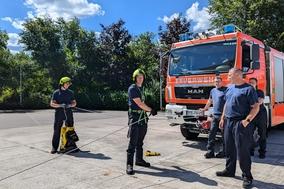 Feuerwehrmänner mit Sicherungsleine vor einem Feuerwehrfahrzeug