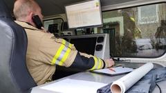 Feuerwehrmann im ELW. Er telefoniert und hat einen Computer vor sich.